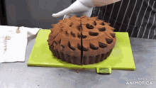 a person is cutting a chocolate cake on a green cutting board made in animatica