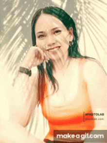 a woman in an orange tank top is smiling in front of a palm tree leaf shadow