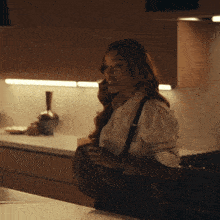 a woman in a striped shirt is standing in a dark kitchen