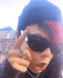 a person wearing sunglasses and a black beanie is making a peace sign