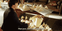 a man is sitting at a table with a pile of papers on it and says that just sort of happened .