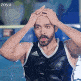 a man in a black adidas tank top is standing in the water