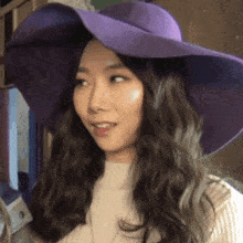 a woman wearing a purple hat and a white sweater is sticking her tongue out
