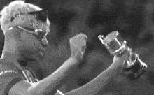a black and white photo of a man holding a trophy in his hands .
