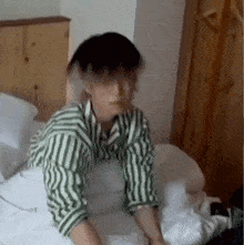 a young man in a striped shirt is laying on a bed .