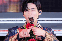 a man is holding a red rose in his hand while holding a microphone in his mouth