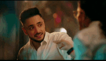 a man in a white shirt is pointing at another man 's face
