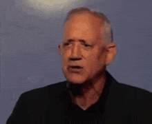 a man wearing a black shirt with the letter r on it is making a funny face