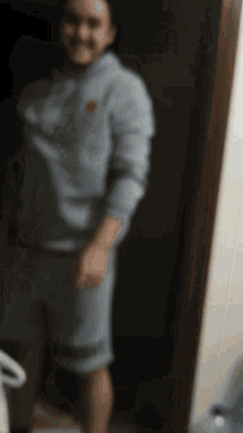 a man in a hoodie and shorts is standing in a dark room
