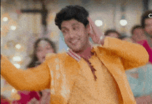 a man in a yellow jacket is dancing in a crowd .