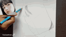 a person is drawing a woman 's face with a blue pencil and a reference image