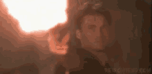 a man is holding a torch in his hand in front of a fire .