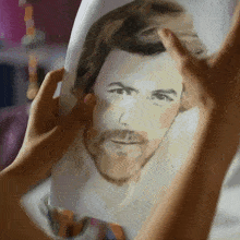 a person is holding a drawing of a man 's face