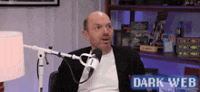 a man is sitting in front of a microphone with the words dark web written on the bottom