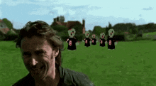a man is standing in a field with a bunch of aliens in the background