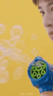 a close up of a man blowing soap bubbles with the name teumae in the corner