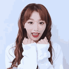 a woman wearing a white sweater and red lipstick looks surprised