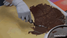 a person is spreading chocolate on a piece of dough and the words made in animotica can be seen in the corner