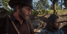 a man in a cowboy hat is standing next to another man in a blue shirt