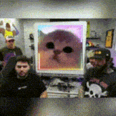 a group of people are sitting in front of a computer screen with a cat on it