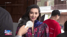 a woman in a floral jacket is being interviewed by a man in a red shirt