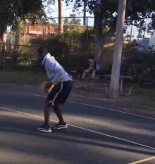 a man is playing basketball on a court while a woman sits on a bench in the background
