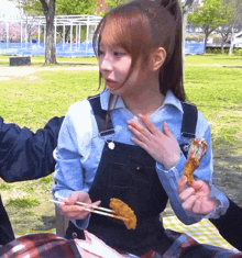 a girl in overalls is holding a piece of food in her hands