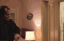 a man standing in a room with a lamp and a mirror on the wall