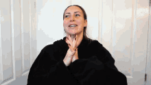 a woman in a black robe is clapping her hands and smiling
