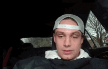 a man wearing a white hat and a black jacket is sitting in a car