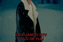 a man in a black coat is standing in the snow with yo cuando soy solo de yuli written in red