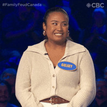 a woman wearing a white sweater and a blue name tag that says gelsey