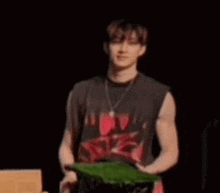a man in a black tank top is standing in front of a podium holding a green leaf .