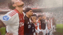 a group of soccer players are standing in a row on a soccer field .
