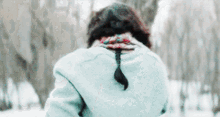 a woman wearing a blue jacket and scarf is standing in the snow
