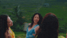 a woman in a blue tank top is running through a field of trees .