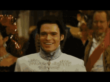 a man in a white suit is smiling in front of a woman