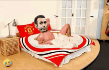 a man laying on a bed with a manchester united blanket on it