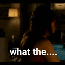 a woman in a dark room with the words what the on the bottom right