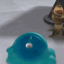 a toy monkey is standing next to a blue toy on a table