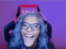 a person with blue hair and glasses is making a funny face .