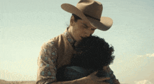 a man in a cowboy hat is hugging a woman