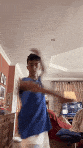 a young man in a blue shirt is playing a video game in a living room