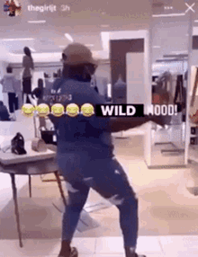 a man in a blue shirt is dancing in a store with the words wild mood written on the bottom