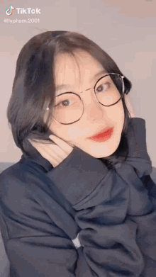 a girl wearing glasses and a black sweater is making a funny face .