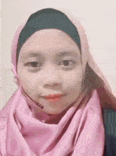 a woman wearing a pink hijab and a headset is smiling .