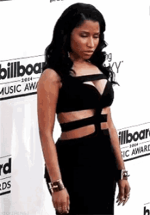 a woman in a black dress is standing on a red carpet in front of a billboard .