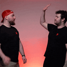 two men are giving each other a high five while wearing black shirts