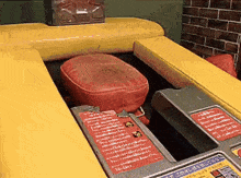 a red pillow sits on top of a yellow table with a sign that says ' warning ' on it