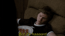 a man is laying on a couch with a plate of bacon and the words but it 's haaard